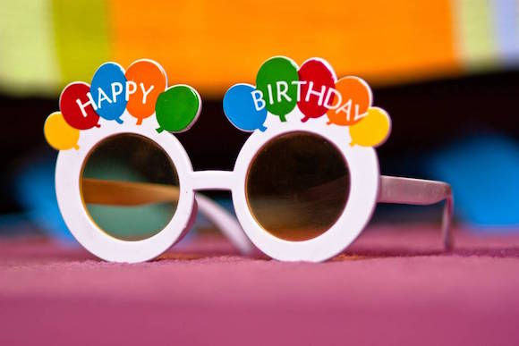 funky birthday glasses on colored background